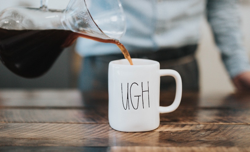 man poring coffee into a mug that says, ugh"